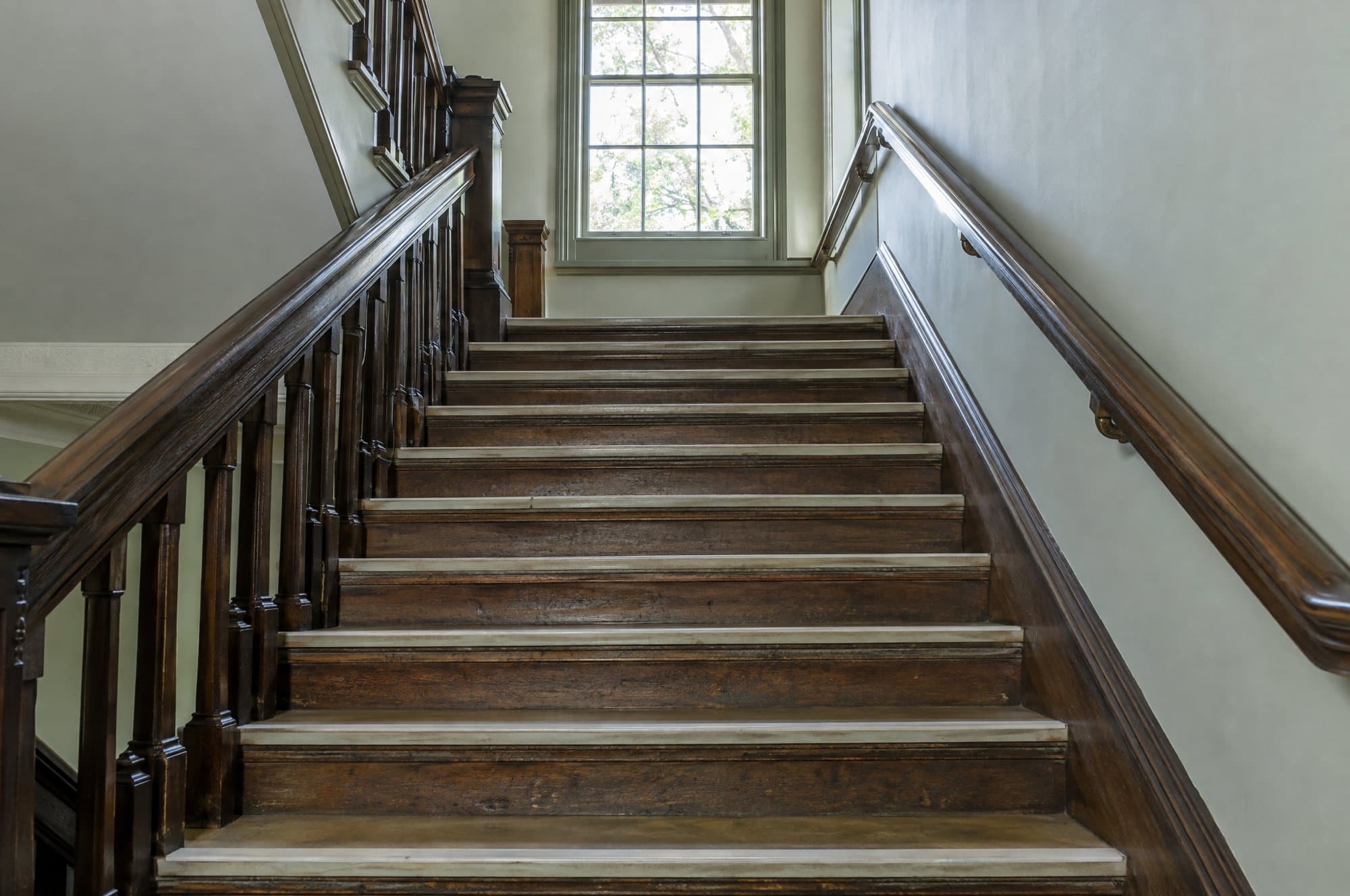 The oak staircase to the upper floor, with handrails on both sides and a light strip on the edge of every step.