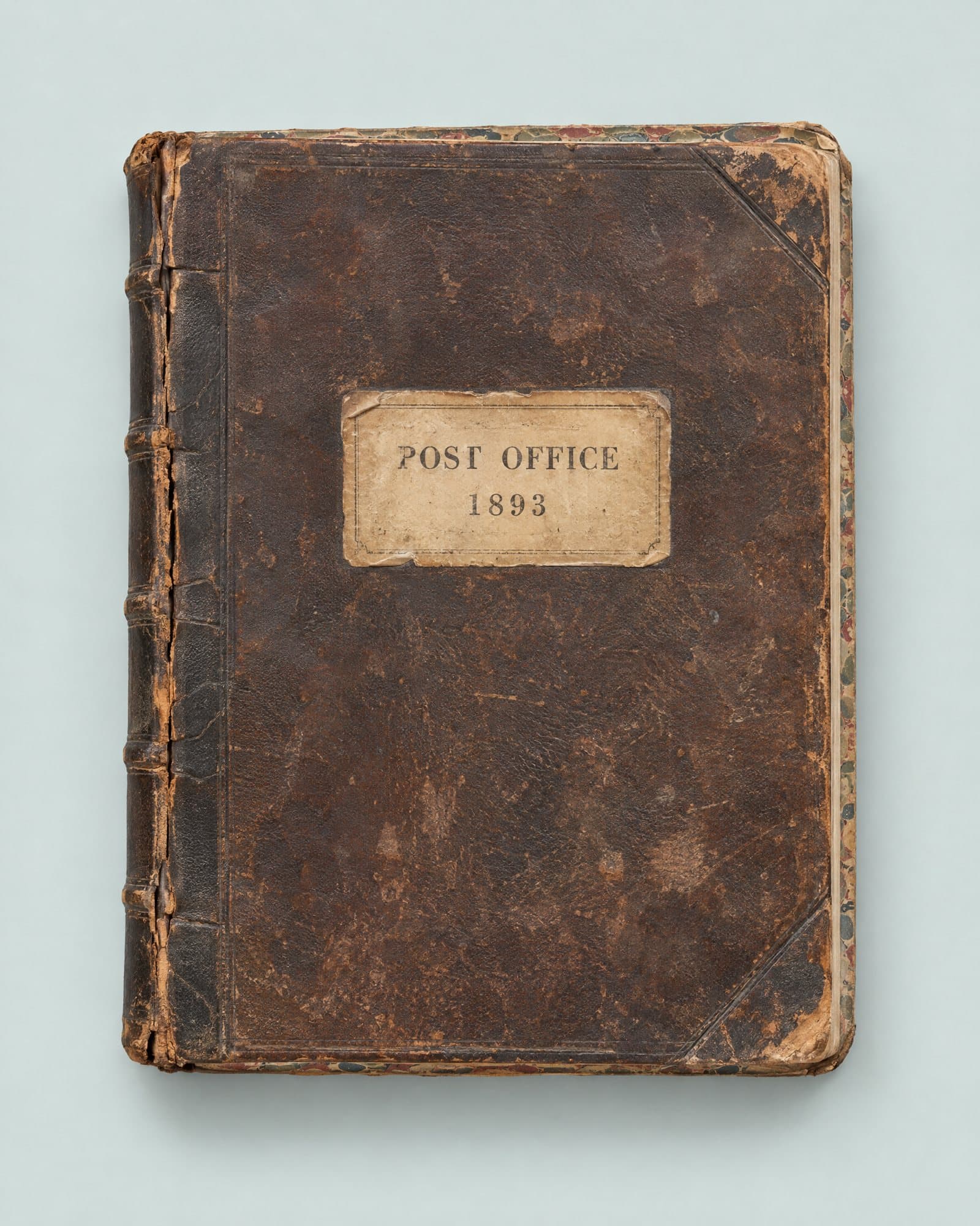 A worn leather ledger with a paper label reading Post Office 1893.