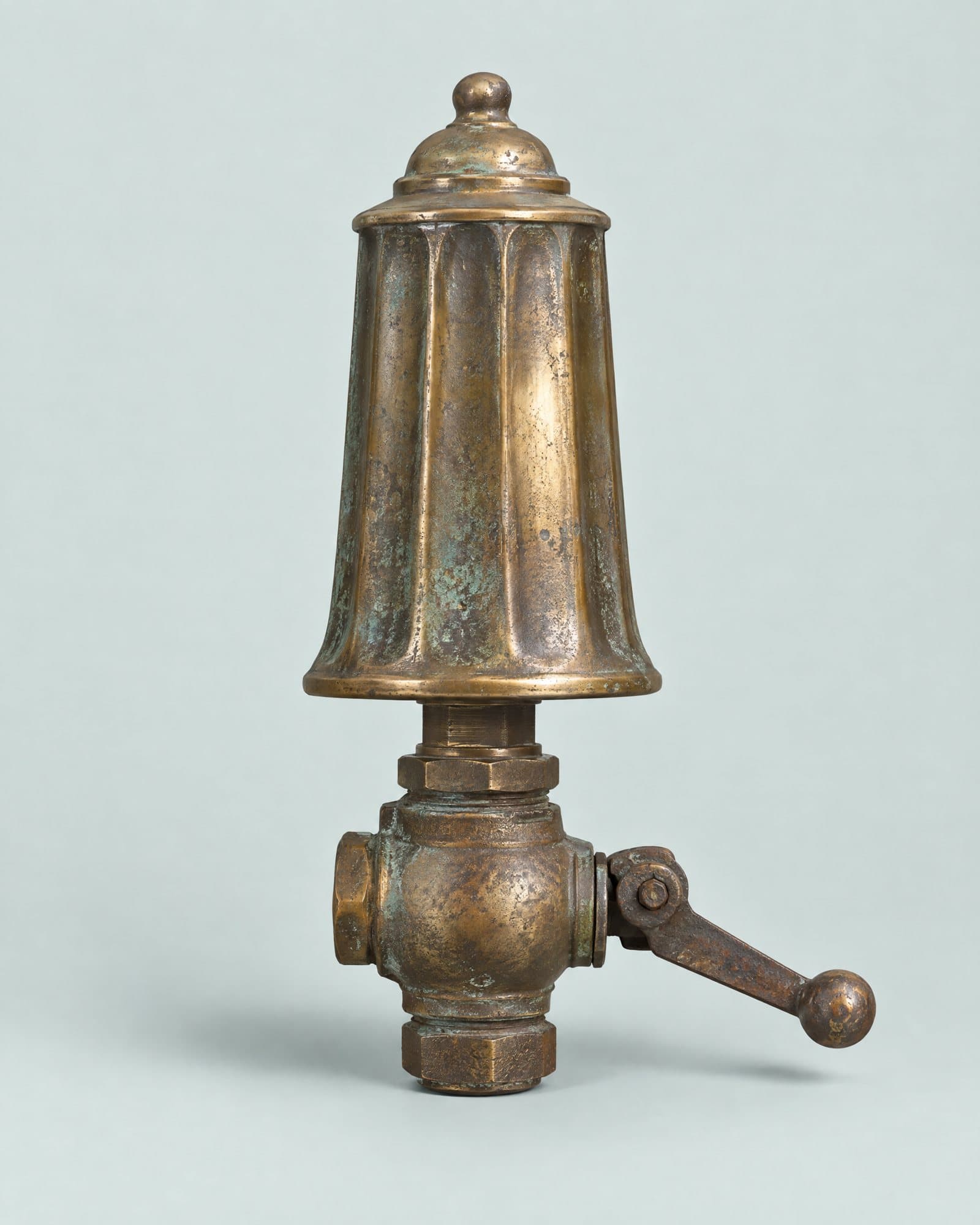 A tall fluted brass steam whistle on a valve with a pull lever.