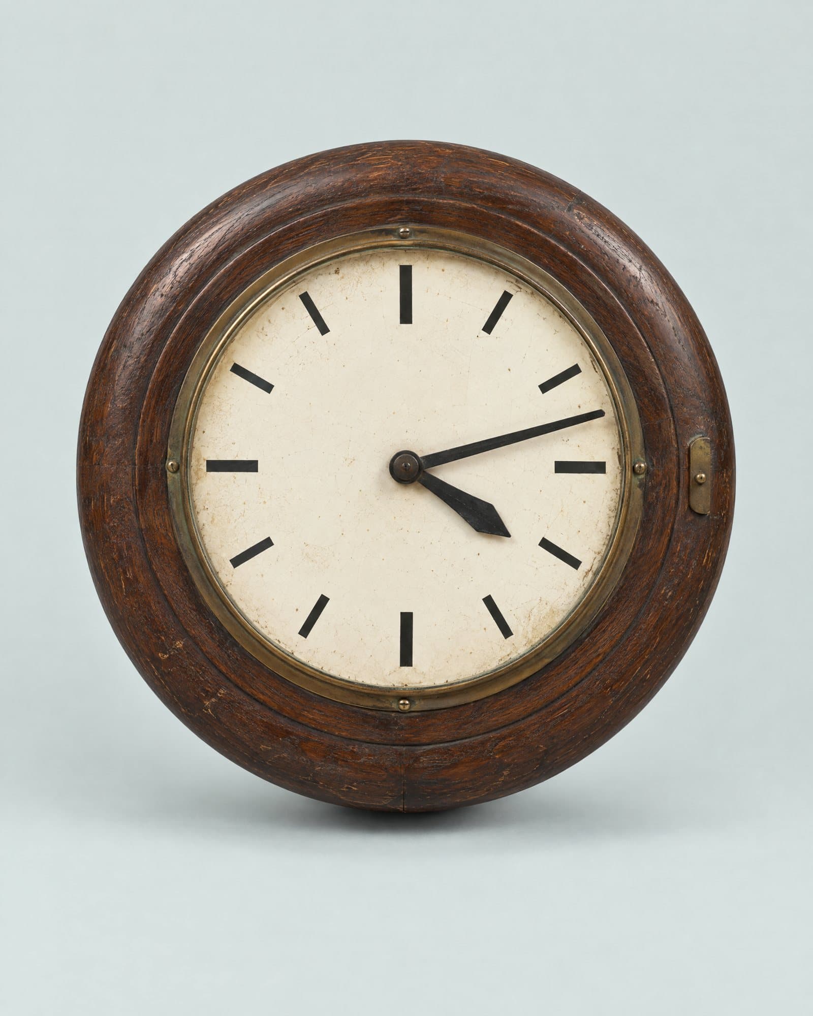A round station clock in a dark wooden case, its hands stopped at 4:12.